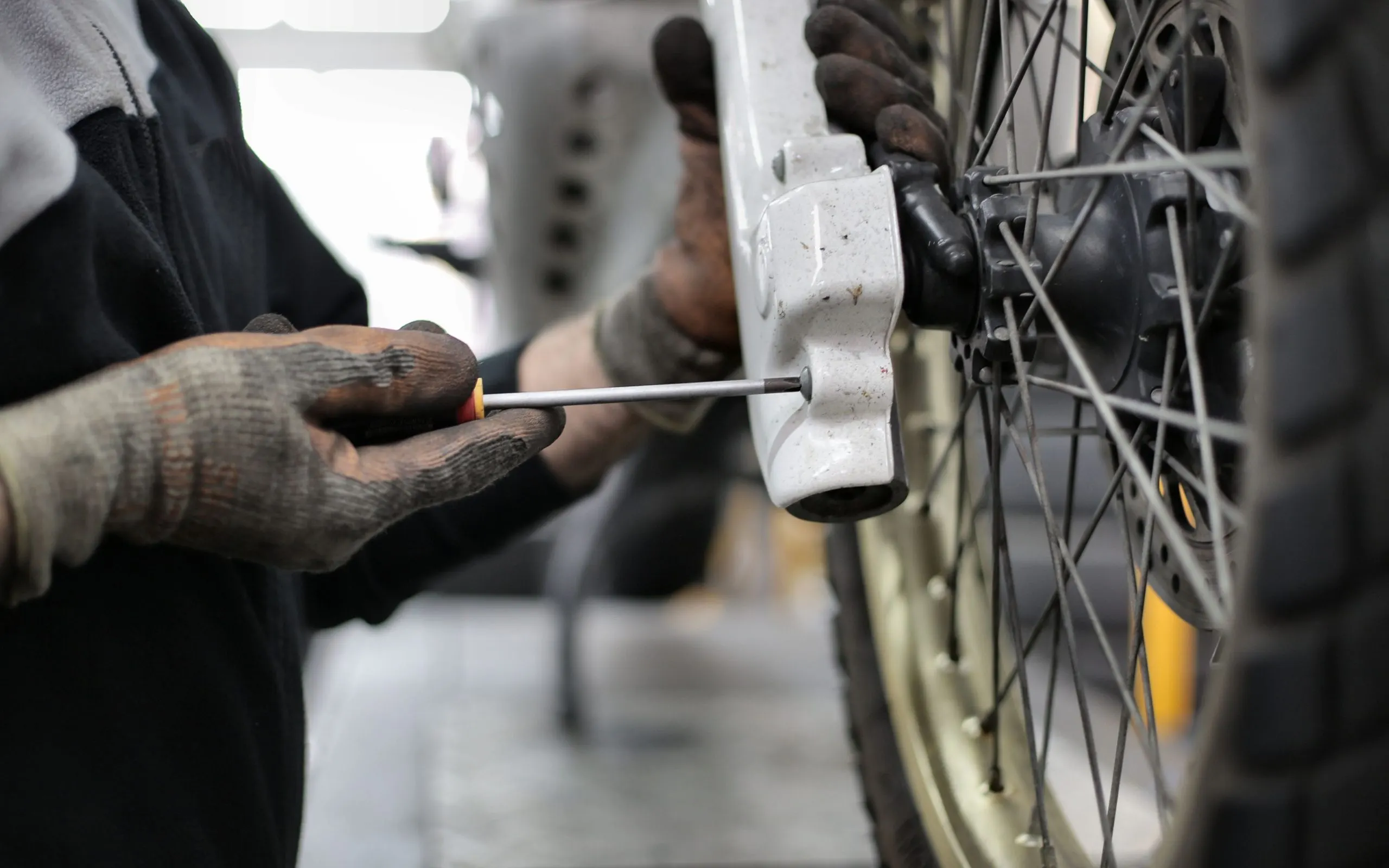 Mécanicien qui resserre une pièce sur une moto dans un atelier propre